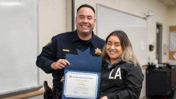 Police officer with UC Davis student and certificate, smiling