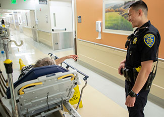 patient gestures toward police officer from a hospital bed