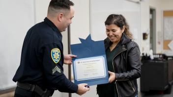 beaming student accepts academy certifiate from UC Davis police officer
