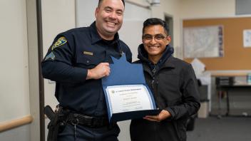 UC Davis police officer with student and certificate, smiling
