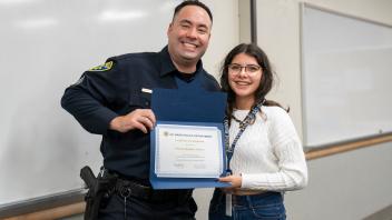 UC Davis students with police officer and certificate, smiling