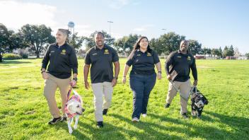 Four core officers walking with K-9s Leia and Cali.