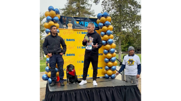 Chief Farrow speaking on stage at the Love on the Run k9 5k event next to CORE Officer Malik and K9 Charlie.