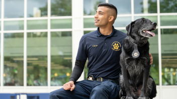 CORE Officer Malik and K9 Charlie sitting in front of the Memorial Union.