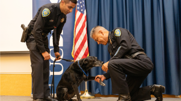 K9 Charlie with his paw raised shaking Chief Farrow's hand after receiving an award.