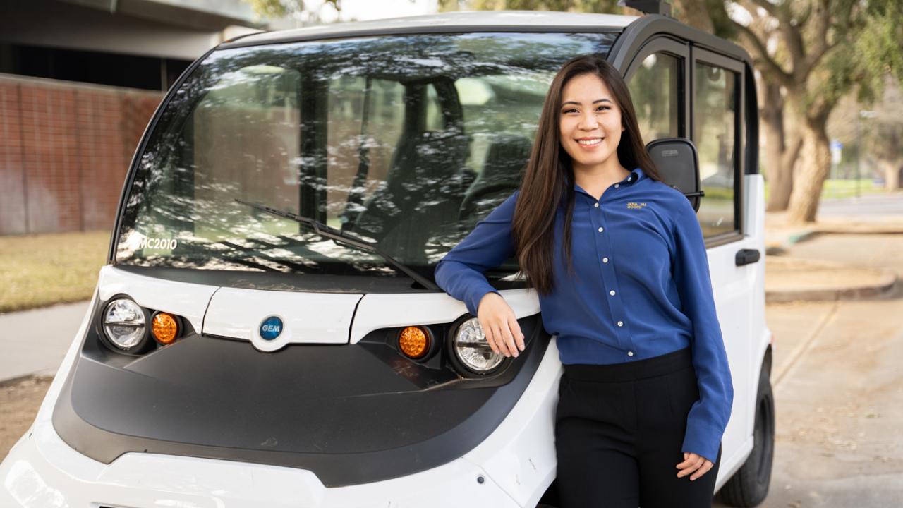 CORE Officer Jena Du smiles and stands next to her electric vehicle