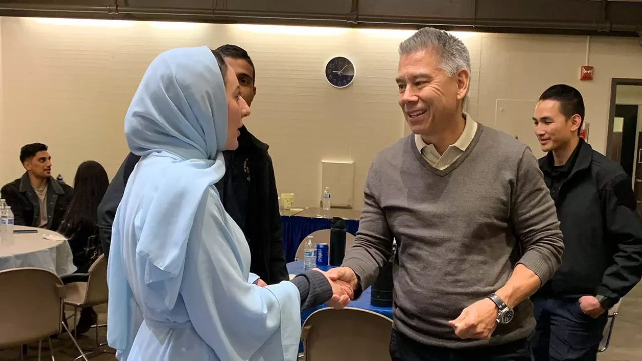 student wearing hijab shakes hands with Joe Farrow