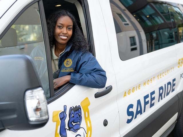 Aggie Host smiling in drivers seat of a Safe Ride van.