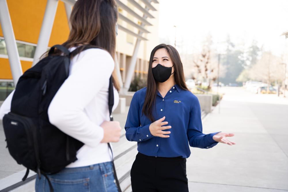 CORE Officer Jena Du wears a face covering and talks to a student on campus