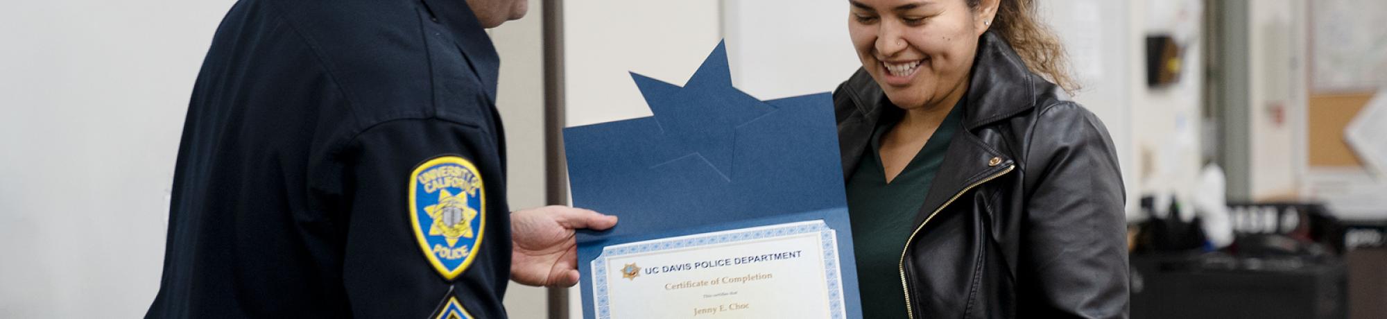 beaming student accepts academy certifiate from UC Davis police officer