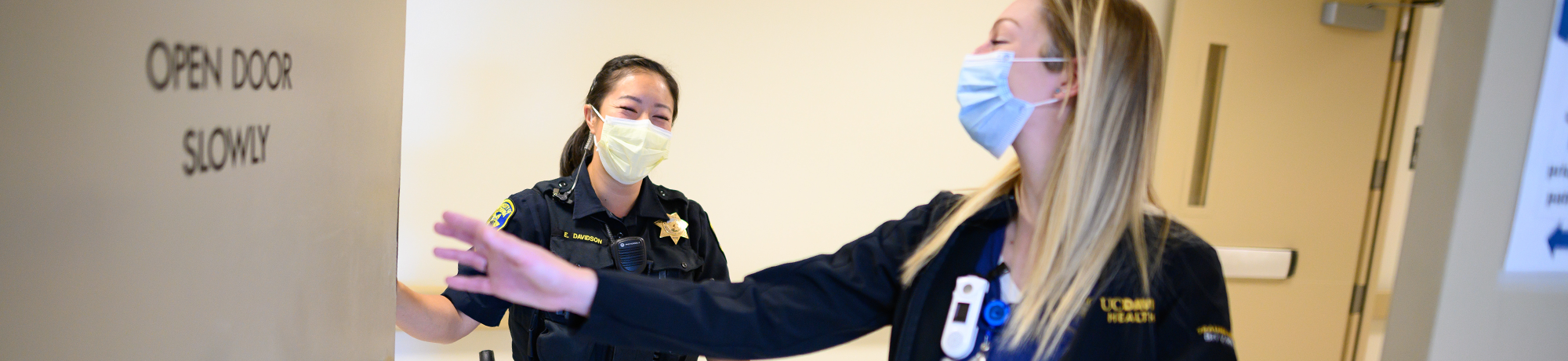 Female officer and nurse with face coverings walk through UC Davis Medical Center