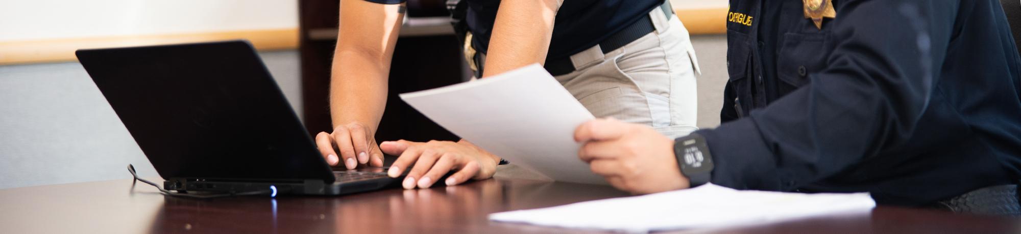 Hands typing and holding paper
