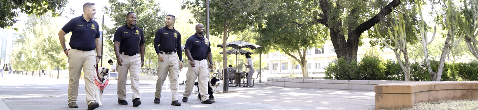 CORE officers and k9s walk through campus with Shields Library in the background.